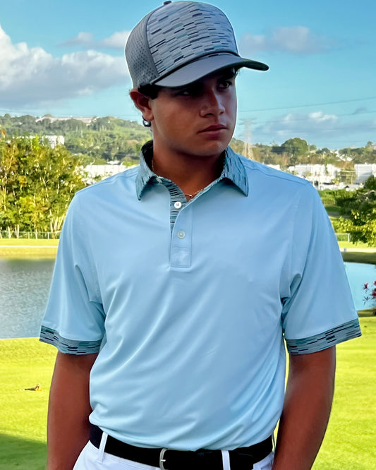 Person wearing a light blue polo shirt and white pants on a golf course with a scenic background.
